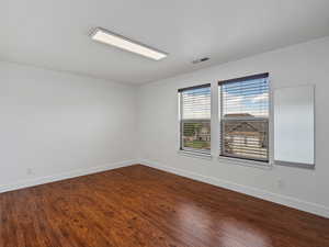 Empty room with baseboards and dark wood-style floors