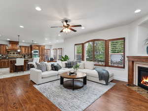 Living area featuring light wood-type flooring, a premium fireplace, ceiling fan, and recessed lighting