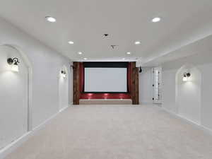 Home theater room featuring arched walkways, light colored carpet, and recessed lighting