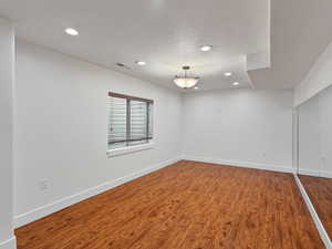 Unfurnished room with wood finished floors, recessed lighting, and a textured ceiling
