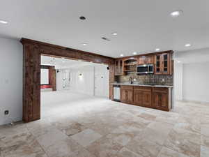 Kitchen with glass fronted cabinets, recessed lighting, decorative backsplash, dark stone counters, and open shelves