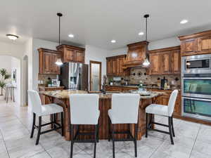Kitchen featuring dark stone countertops, arched walkways, decorative light fixtures, and a kitchen breakfast bar