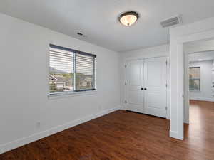 Unfurnished bedroom with dark wood-type flooring and a closet