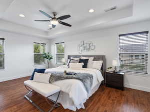 Bedroom featuring a raised ceiling, recessed lighting, dark wood finished floors, and ceiling fan