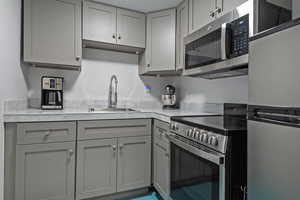 Kitchen with gray cabinetry, stainless steel appliances, and light countertops