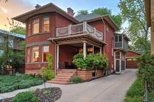 View of front of property with a chimney, a garage, brick siding, and a sunroom