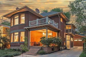 View of front of home with a chimney, brick siding, and a balcony