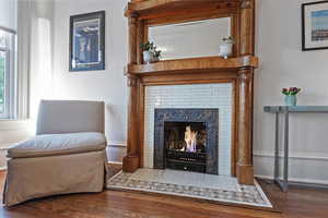 Living area with dark wood-type flooring and a warm lit fireplace