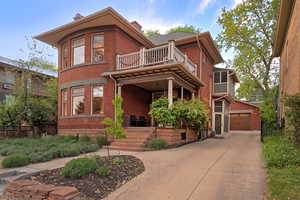 View of front of property with a chimney, brick siding, a balcony, and a garage