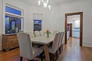 Dining room featuring hanging lights, dark wood finished floors, and ornamental molding