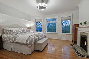 Bedroom with light wood-type flooring, wainscoting, and a tile fireplace