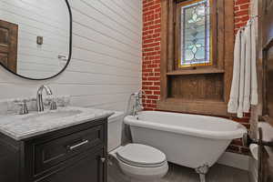 Bathroom featuring wooden walls, vanity, and a freestanding bath