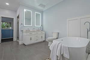 Full bathroom featuring a freestanding tub, double vanity, a stall shower, ornamental molding, and recessed lighting