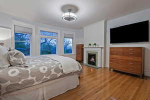 Bedroom with light wood finished floors and a lit fireplace