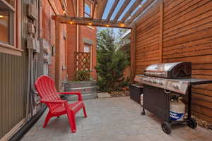 View of patio with grilling area and a pergola