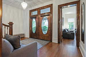 Foyer featuring dark wood-type flooring, plenty of natural light, and suspended lighting