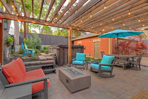 Fenced backyard with an outdoor fire pit, a patio area, a pergola, and a hot tub