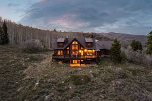 Back of property with a deck, a standing seam roof, and a chimney