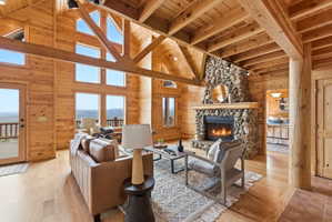 Living area with wood walls, a fireplace, light wood-style flooring, a high wood beamed ceiling, and a mountain view