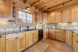 Kitchen featuring a wooden ceiling with exposed beams, open shelves, track lighting, dark stone counters, and light tile patterned flooring