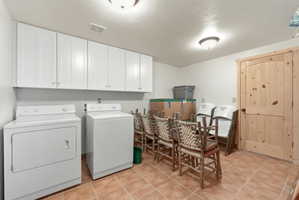 Laundry area with washer and dryer, cabinet space, and light tile patterned floors