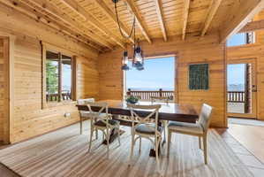 Dining space with hardwood / wood-style flooring, wood walls, hanging lights, and a wood ceiling with exposed beams