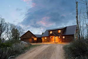Log-style house featuring driveway, a metal roof, and a garage