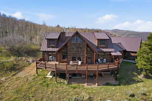 Back of property featuring a deck with mountain view, a metal roof, and a chimney