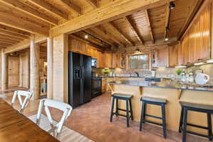 Kitchen with open shelves, a wood ceiling with exposed beams, black appliances, rail lighting, and a peninsula