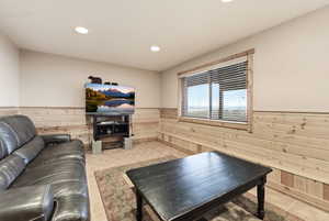 Living room featuring a wainscoted wall, wooden walls, recessed lighting, and light tile patterned flooring