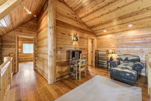 Sitting room featuring hardwood / wood-style floors, a vaulted wooden ceiling, and wooden walls