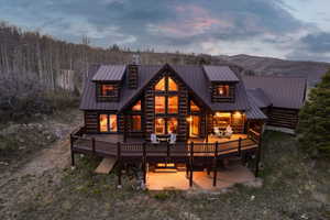 Back of property at dusk featuring a deck with mountain view, a chimney, and a metal roof