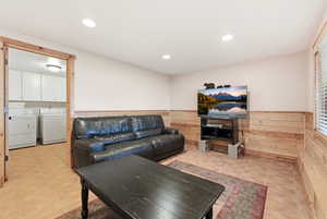 Living area featuring wainscoting, recessed lighting, washing machine and clothes dryer, light tile patterned floors, and wooden walls