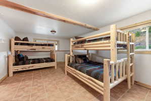 Bedroom with light tile patterned floors and beam ceiling