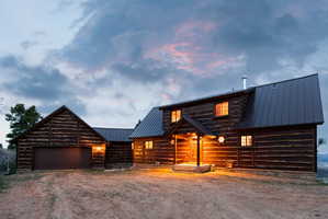 Log cabin with a metal roof, driveway, and an attached garage