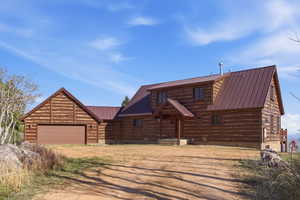 Cabin featuring driveway, a garage, and a metal roof