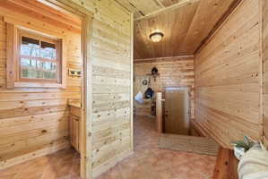 Hall featuring wood walls, wood ceiling, and light tile patterned flooring