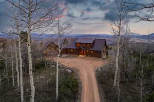 View of front of home featuring a metal roof, a mountain view, log siding, and driveway