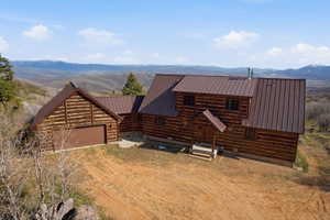 Log cabin with a mountain view, a metal roof, a garage, and dirt driveway