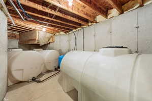 Unfinished basement featuring oil tank and a water pressure tank