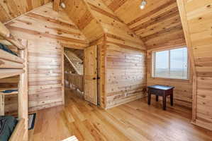 Unfurnished bedroom featuring wood-type flooring, wooden walls, and a vaulted wood ceiling