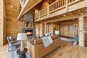 Living area with wood walls, light wood finished floors, a fireplace, and a high wood ceiling