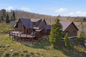 Rear view of property with a deck, a standing seam roof, and a patio area