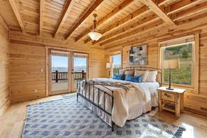 Bedroom with wooden walls, light wood-style flooring, a wood ceiling with exposed beams, and access to outside