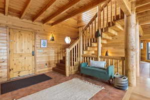 Entryway featuring wooden walls, a wood ceiling with exposed beams, and tile patterned flooring