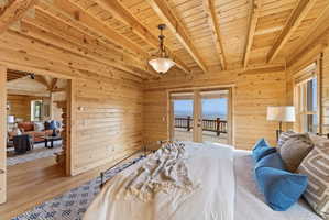 Bedroom featuring french doors, a wooden ceiling with exposed beams, wood walls, access to exterior, and wood finished floors