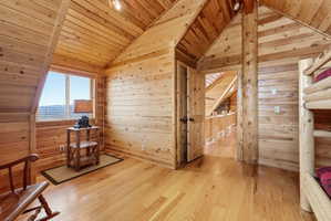 Sitting room featuring light wood finished floors, wooden walls, and a vaulted wooden ceiling