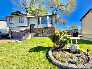 Bi-level home with brick siding, a front yard, and a garage