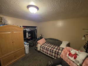 Bedroom with a closet, dark colored carpet, and a textured ceiling