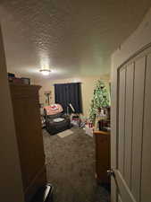 Bedroom featuring dark colored carpet, a textured ceiling, and a closet